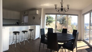 A modern kitchen with white cabinets, a bar stool area, and a dining table with chairs. - Kendall Yards Home - Stunning views, amazing downtown location (Spokane)