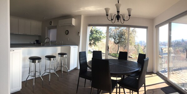Een moderne keuken met witte kasten, een bar met barkrukken en een eettafel met stoelen.