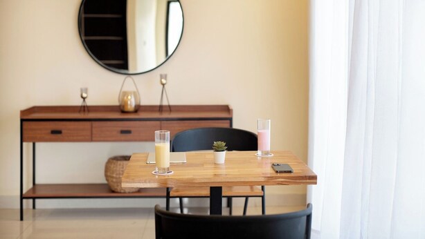 A modern room with a wooden desk, a round mirror, a potted plant, and a glass of milk. - Purple Cloud Urban (Bengaluru)