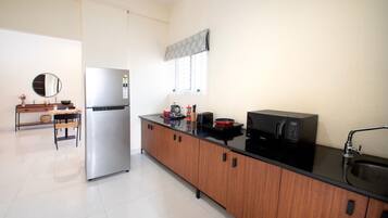 Una cocina moderna con un refrigerador de acero inoxidable, un microondas y una encimera negra.