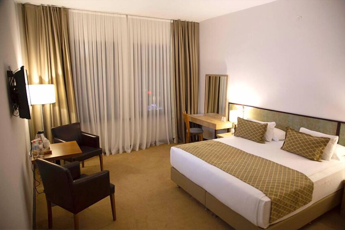 A hotel room with a bed, a desk, a chair, and a TV.