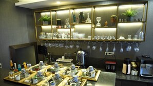 Un espace bar avec des étagères où sont exposés des verres, une machine à café et une grande marmite.
