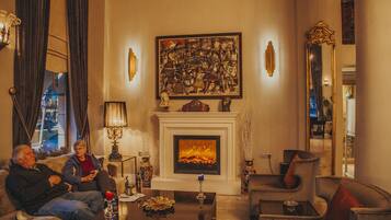 Una sala de estar acogedora con chimenea, asientos cómodos y un cuadro grande en la pared.