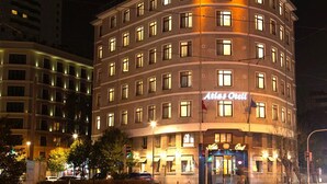 Un hôtel à plusieurs étages, doté d’une façade incurvée, de fenêtres illuminées et d’une entrée bien visible avec une enseigne.
