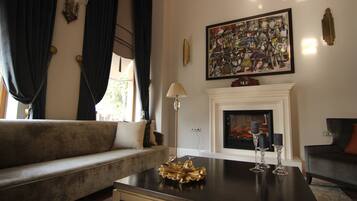 A living room with a sofa, a coffee table with decorative items, a fireplace, and a large abstract painting on the wall.