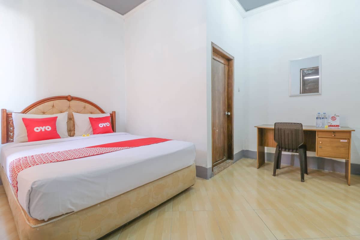 A hotel room with a bed, a desk, and a chair.
