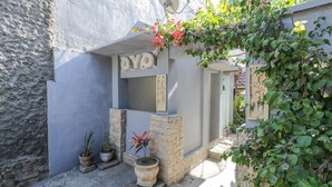 A courtyard with a stone wall, a potted plant, and a sign with the word "YOYO". - OYO 1514 Rara Inn (Kuta)
