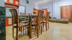 A dining area with wooden chairs and a table, a sofa, and a curtain. - OYO 1514 Rara Inn (Kuta)
