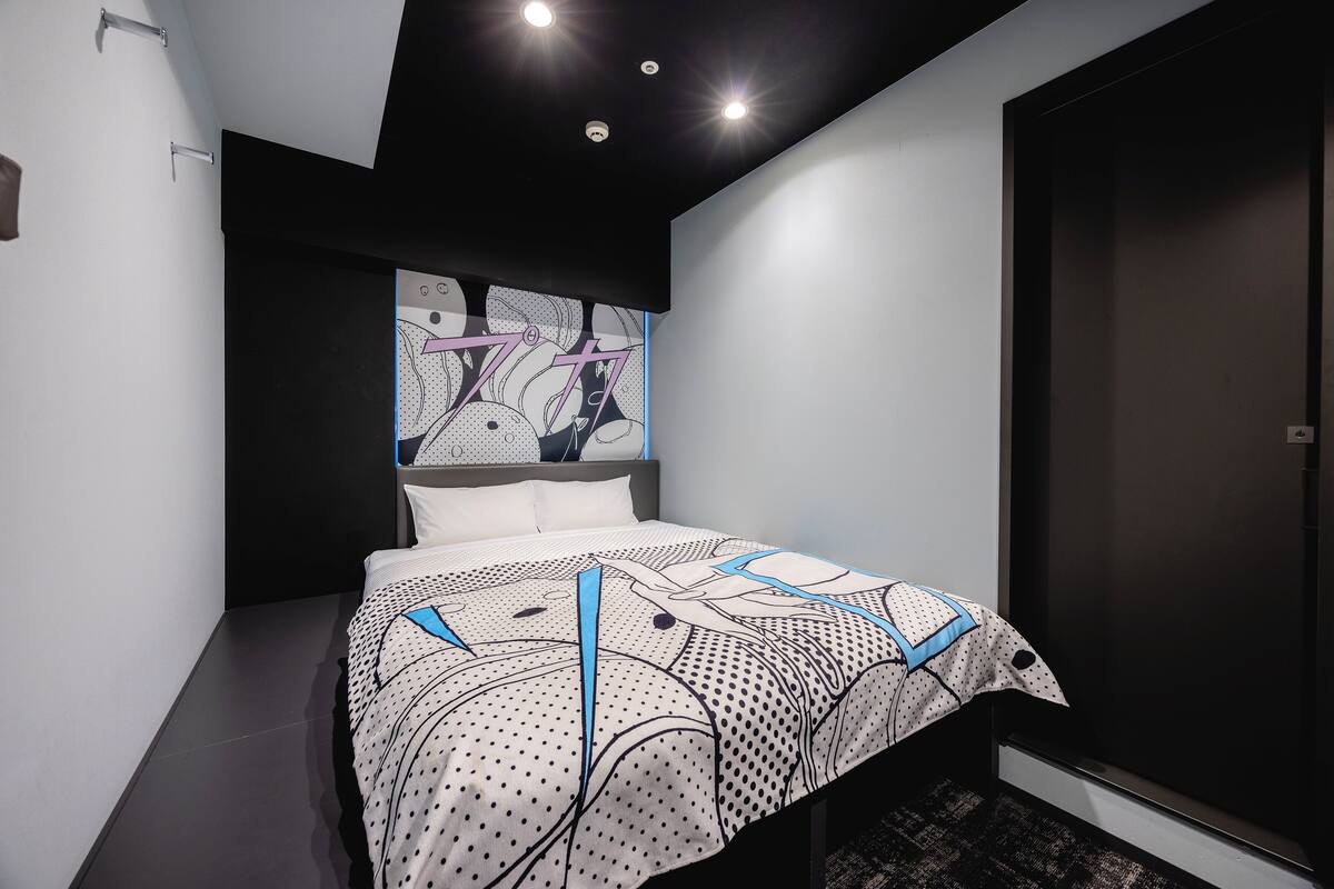Une chambre à coucher moderne avec un lit, une tête de lit au motif graphique, une porte sombre et une petite fenêtre.