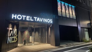Una entrada de hotel moderna con un letrero destacado que dice "HOTEL TAVINOS".