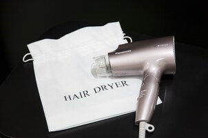 Un secador de pelo sobre una mesa con un paño blanco que dice 'HAIR DRYER'.