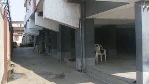 A narrow alleyway with a row of buildings on one side and a covered area on the other. There is a white plastic chair in the covered area. - 44 Lodge And Suites (Lagos)