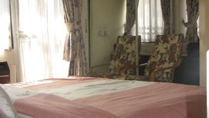 A hotel room with a bed, a chair, and curtains. - 44 Lodge And Suites (Lagos)