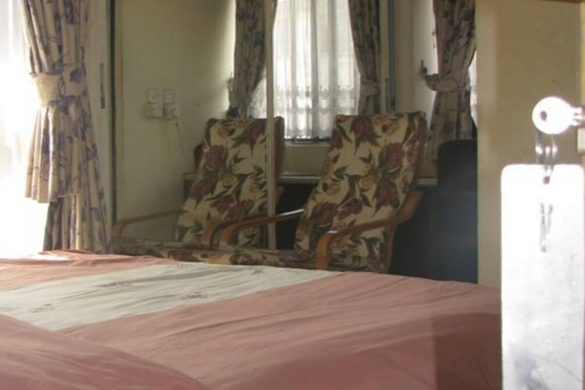 A hotel room with a bed, a chair, and curtains.