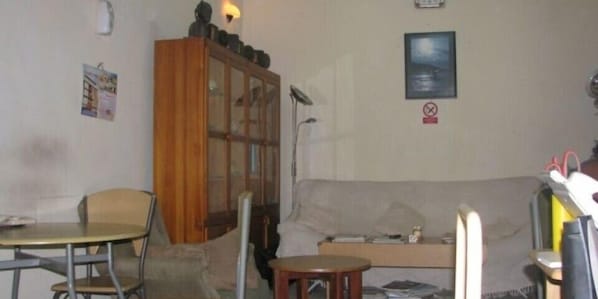 A living room with a wooden cabinet, a sofa, a small table, and a chair.