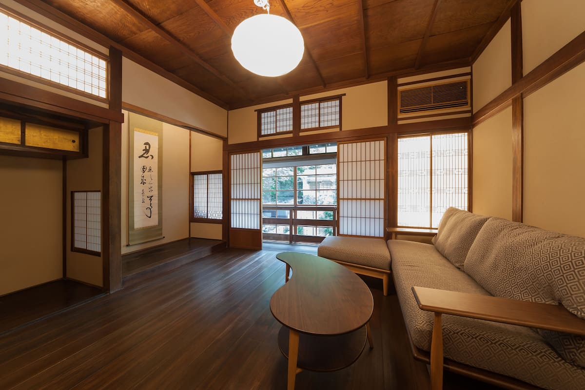 A traditional Japanese room with tatami flooring, a low table, a sofa, and sliding shoji doors.