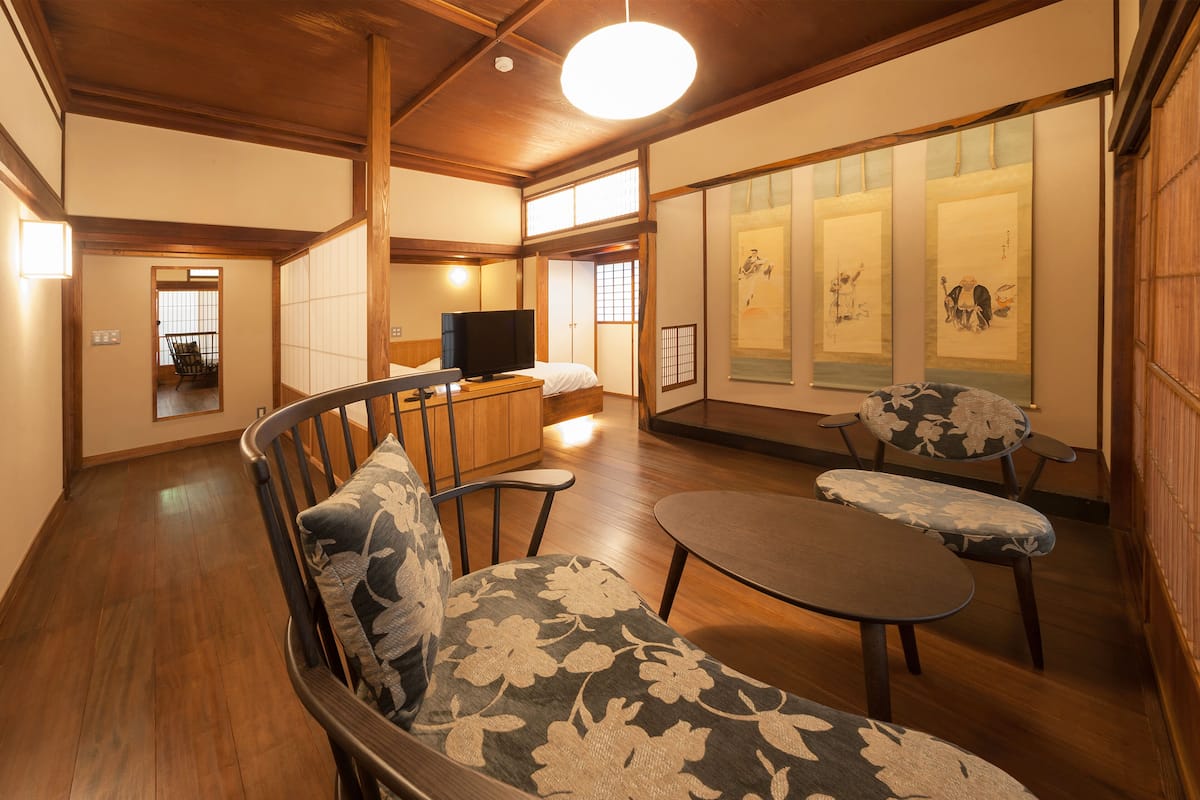 A traditional Japanese-style living room with tatami flooring, a low wooden table, and a sofa with floral cushions.