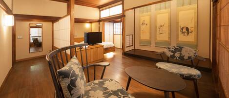 Un salón de estilo japonés tradicional con suelo de tatami, una mesa de madera baja y un sofá con cojines estampados.
