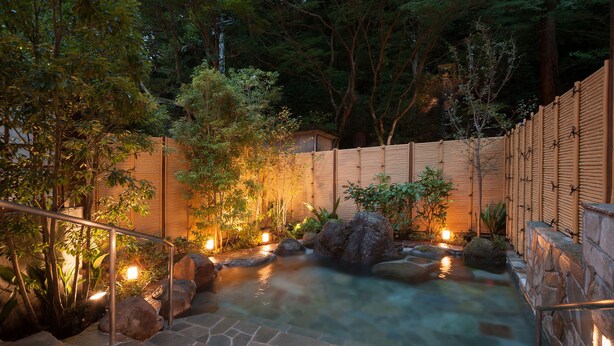 A stone staircase leading to a hot spring surrounded by wooden fences and illuminated by soft lighting. - KANSUIRO Annex (Hakone)