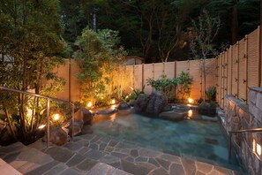 A stone staircase leading to a hot spring surrounded by wooden fences and illuminated by soft lighting. - KANSUIRO Annex (Hakone)