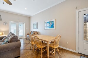 A dining area with a wooden table and chairs, a sofa, and a door with a glass panel.