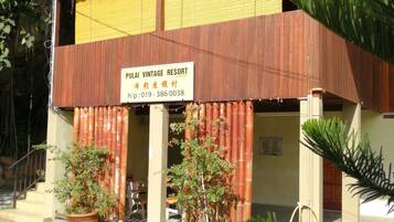 A two-story building with a sign reading "PUILAI VINTAGE RESORT". There are two large potted plants in front of the entrance.