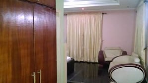 A room with a wooden wardrobe, a sofa, and a bed. - De Boss Deluxe Hotel (Lagos)