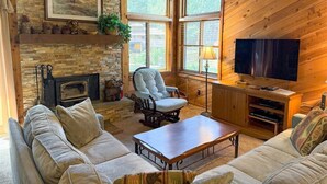 A cozy living room with a fireplace, wooden walls, a television, and comfortable seating. - Wildflower 48: Walk to Town & Green Line Shuttle (Mammoth Lakes)