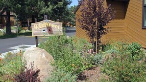 A sign for 'Wildflower' with a garden in front, a wooden building, and a road in the background. - Wildflower 48: Walk to Town & Green Line Shuttle (Mammoth Lakes)