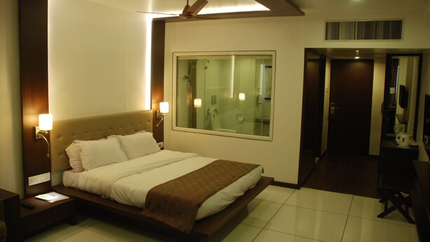 Habitación de hotel con una cama grande, una mesita de noche, una lámpara de pared y un ventilador de techo.