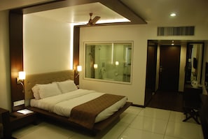A hotel room with a large bed, a nightstand, a wall-mounted lamp, and a ceiling fan.