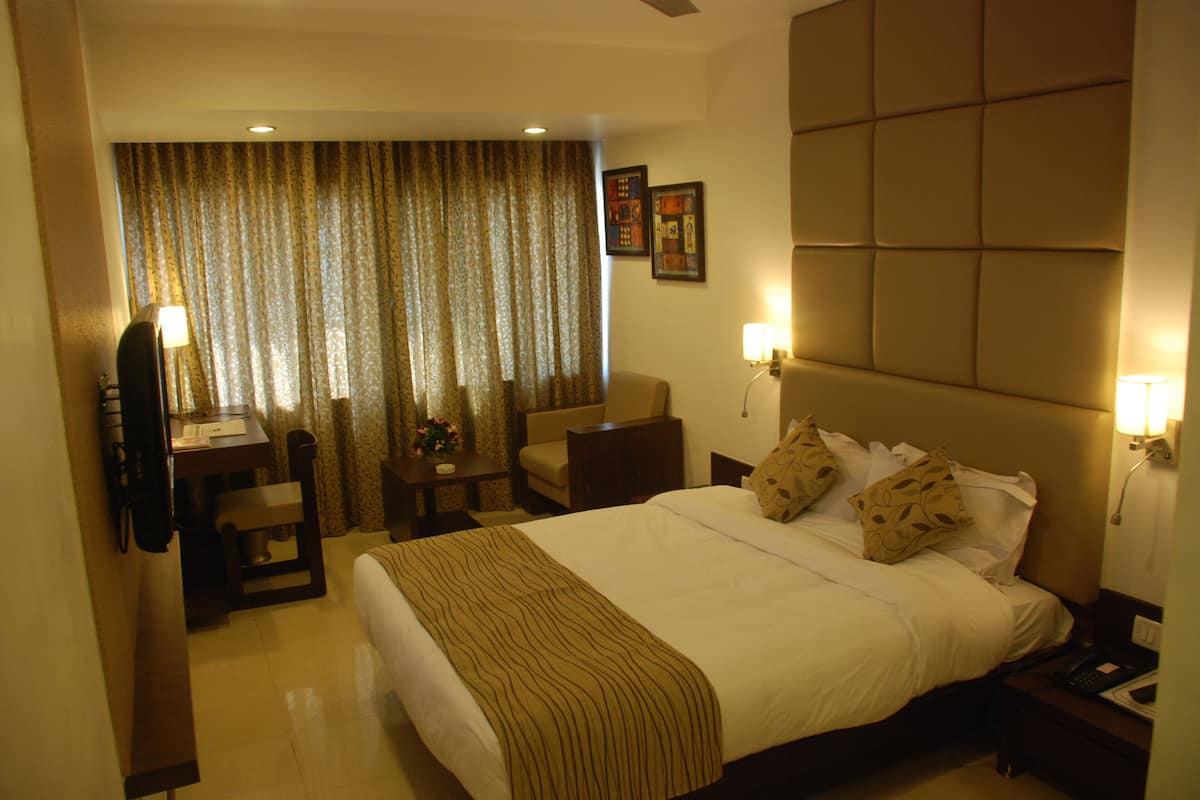 Habitación de hotel con cama, escritorio, silla, sofá y televisión.