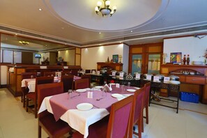 A dining area with tables set for service, a buffet station, and a kitchen area.