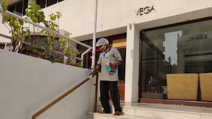 Una persona limpiando una escalera exterior a un edificio con un cartel que dice "VEGA".