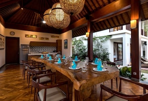 Enjoy meals in this dining area with a long table, chairs, and framed artwork on the walls.