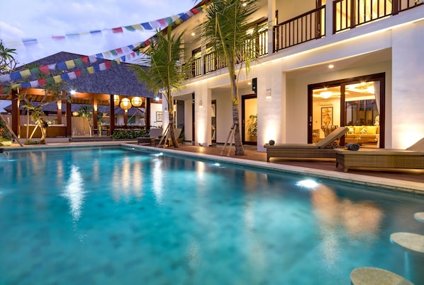 Relax by the serene pool surrounded by lounge chairs and a covered seating area.