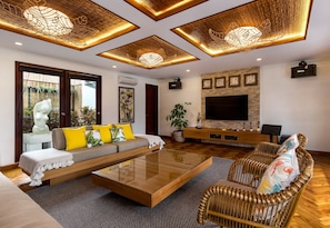 Relax in this stylish living room with a large flat-screen TV, comfortable sofa, and wicker armchair.