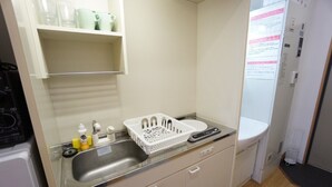 A small kitchenette with a stainless steel sink, a white countertop, a dish rack, and a refrigerator. - Apartment VR Hakuyu Motomachi Namba (Osaka)