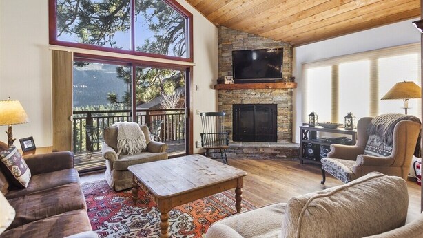 A cozy living room with a stone fireplace, large windows, and a wooden ceiling. - Meadow Ridge: Beautiful Views, Close to Eagle Lodg (Mammoth Lakes)