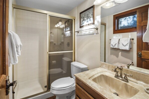 A bathroom with a glass-enclosed shower, a toilet, a sink with a mirror, and a towel rack. - Meadow Ridge: Beautiful Views, Close to Eagle Lodg (Mammoth Lakes)