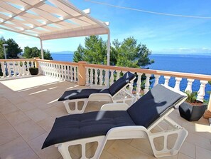 Un espace extérieur abrité, aménagé avec deux fauteuils et un pot de fleurs.
