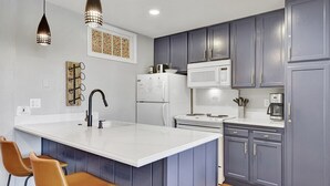 A modern kitchen with grey cabinets, a white island, and pendant lighting. - Crestview 55: Pet Friendly, Close to The Village (Mammoth Lakes)