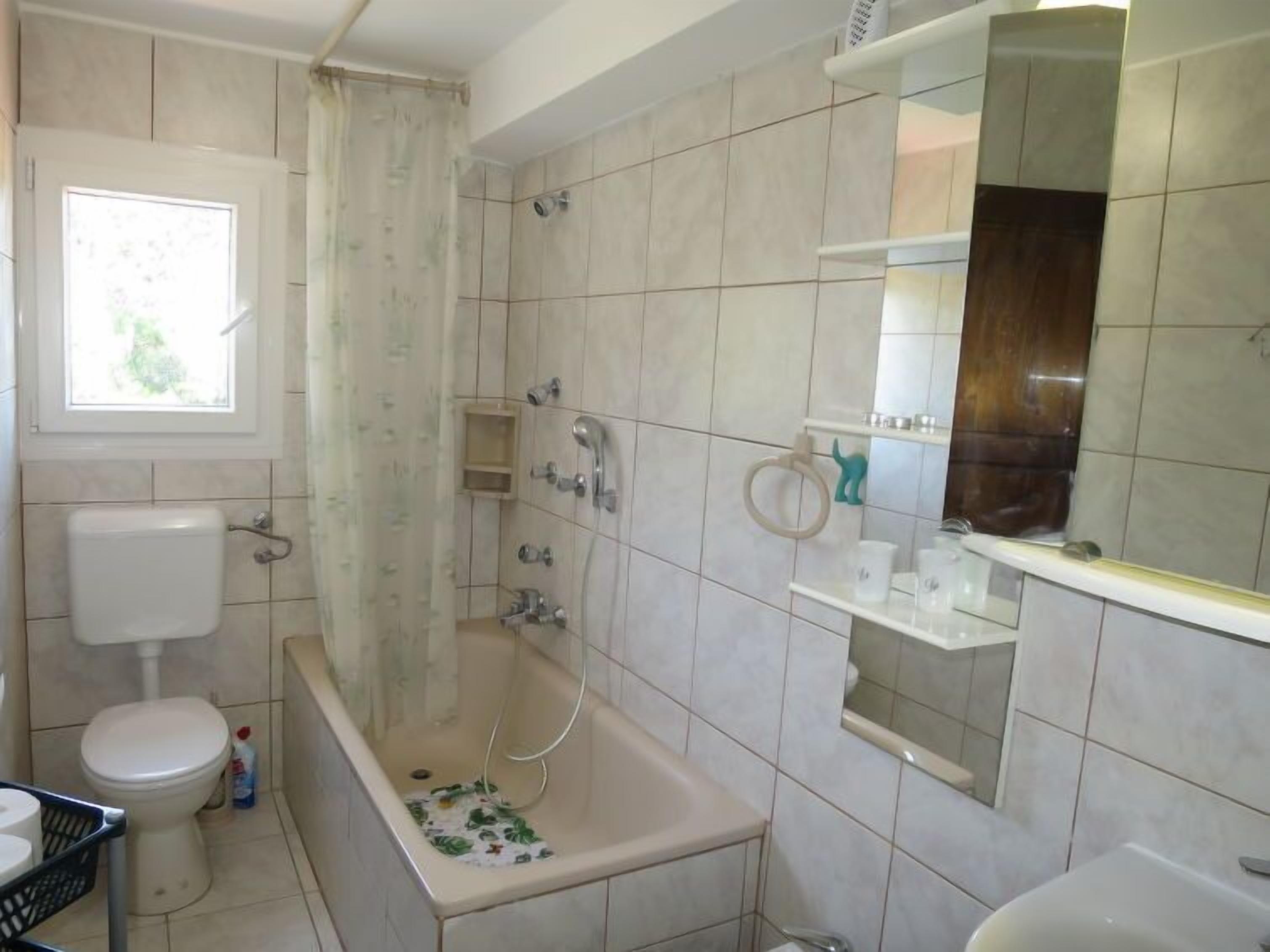Ein Badezimmer mit Badewanne, Toilette und Fenster.