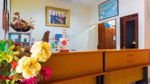 Un comptoir d’accueil orné d’un vase de fleurs, d’une photo de famille encadrée et d’une carte accrochée au mur.