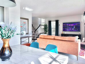 Uma sala de estar moderna com um sofá, uma mesa de jantar e uma televisão.