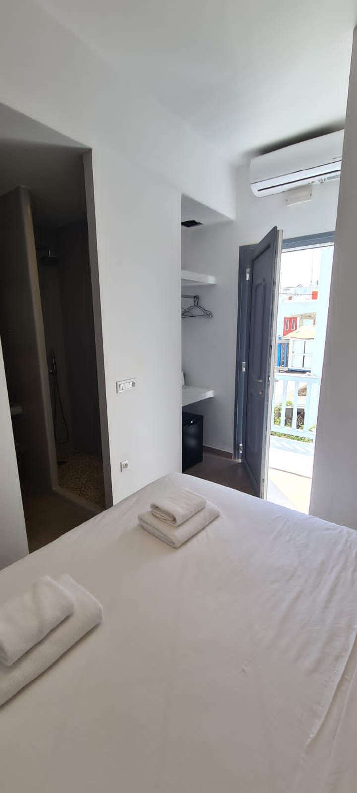 A hotel room with a bed, a bathroom, and a view of the outside.