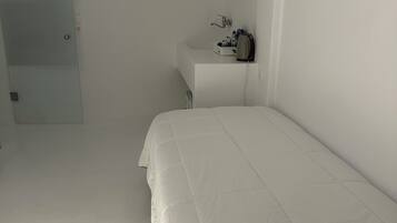 A bedroom with a bed, a bedside table, a mirror, and a door.