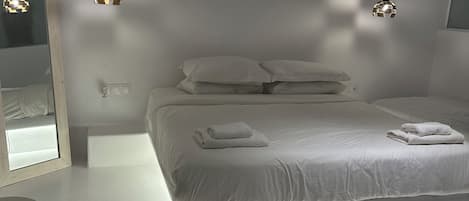 Un dormitorio moderno con una cama grande, dos lámparas colgantes, una mesita de noche y un espejo.