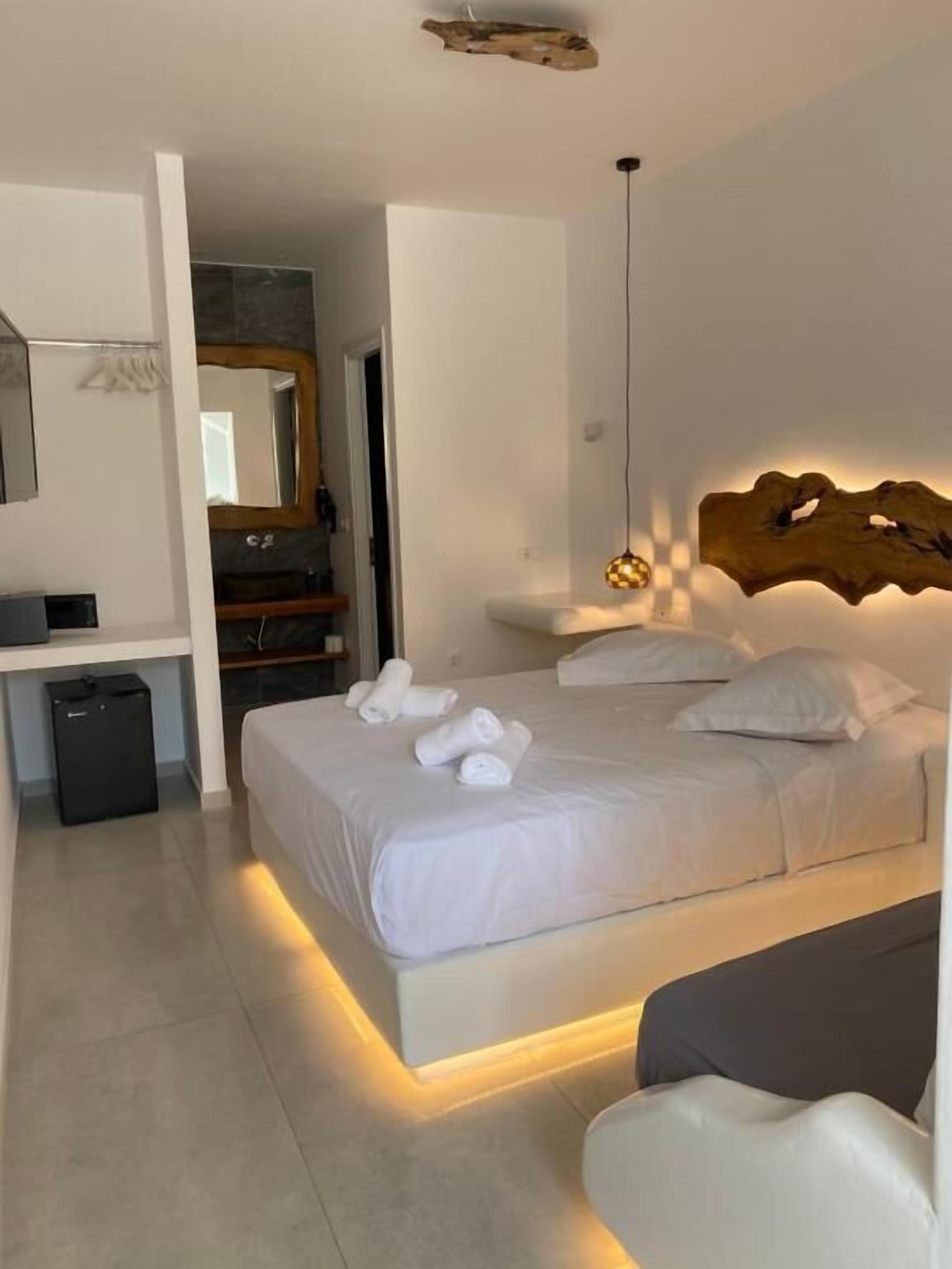 Een moderne hotelkamer met een groot bed, een bureau en een spiegel.
