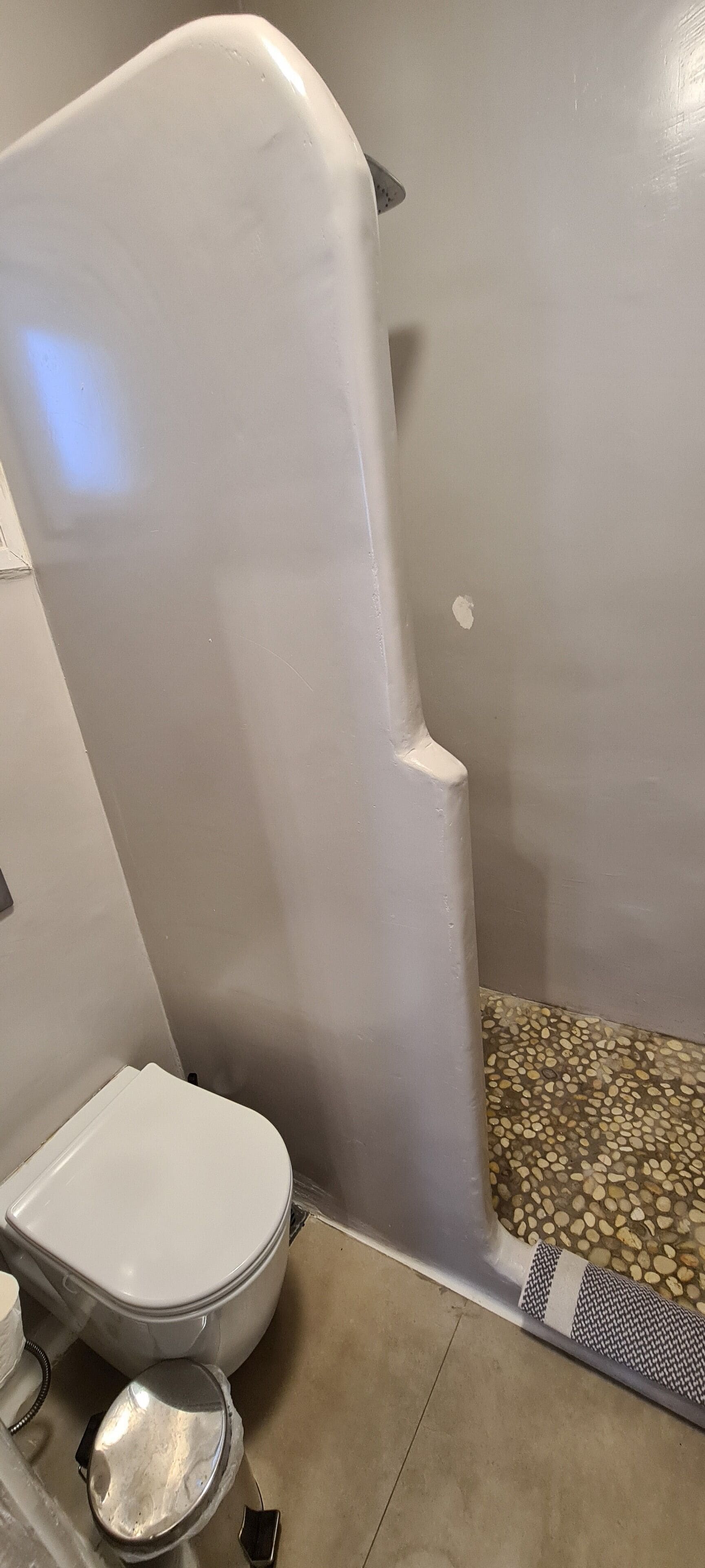 A bathroom with a toilet, a shower area, and a patterned floor.